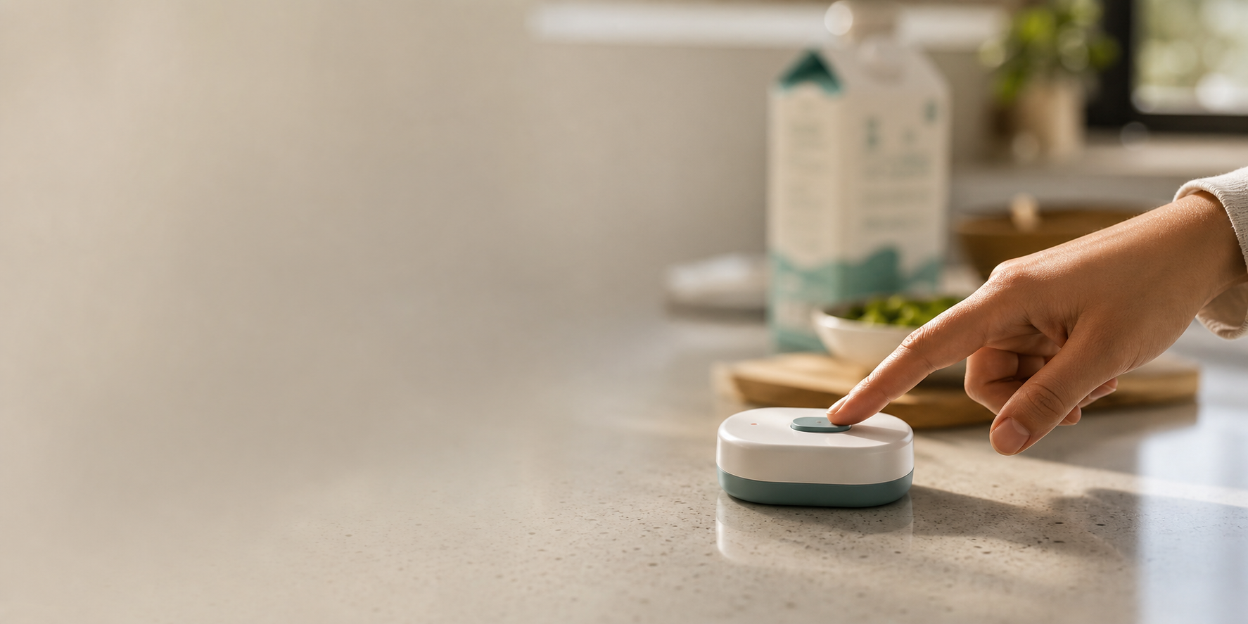 A hand pressing a small Piclu household memory button on a kitchen counter
